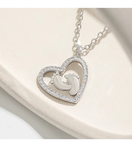 Detailed shot of silver heart necklace with baby footprints and crystal inlay
