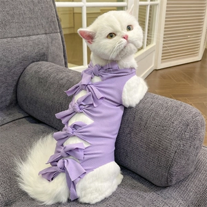Purple cat recovery suit with ribbed cotton fabric and back bow ties on grey sofa