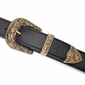 Close-up of vintage engraved gold buckle and hardware on black leather belt for women