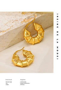 Detailed close-up of 18K gold-plated hollow croissant earrings on textured stone