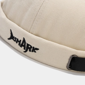 Detail of shark embroidery and adjustable metal buckle on beige cotton docker hat