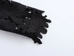 Dettaglio macro della trama floreale in pizzo nero sulla manica della camicia