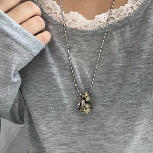 Close-up of spotted stone pendant necklace featuring marble texture beads on silver chain