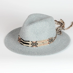 Detailed close-up of woven fedora hat with blue straw texture and bohemian tassel band
