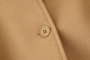 Detailed macro shot of a camel wool coat featuring a classic four-hole matching button