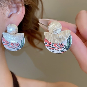 Détail de boucles d'oreilles rondes en bois avec peinture de cactus et métal brossé