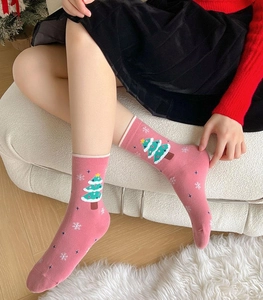 Detail showing pink feather yarn Christmas tree pattern socks worn by model on a sofa