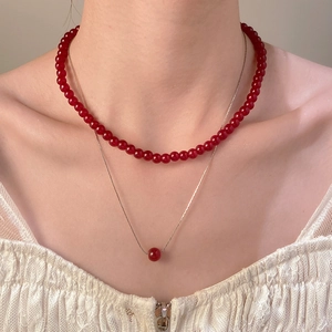 Vista de detalle del collar de doble capa con cuentas rojas redondas y cadena de metal plata