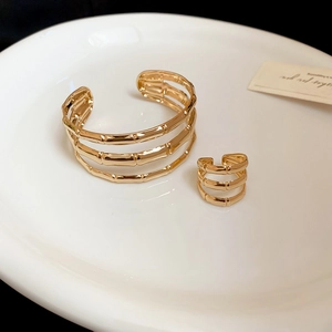 Detail of gold bamboo texture bracelet and ring set on a ceramic plate for women