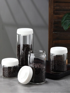 Detail of four glass vacuum sealed canisters with matte white lids for coffee bean storage