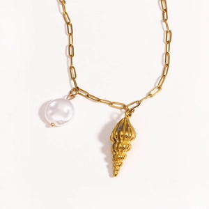 Close-up of golden stainless steel chain with white pearl and conch shell charms