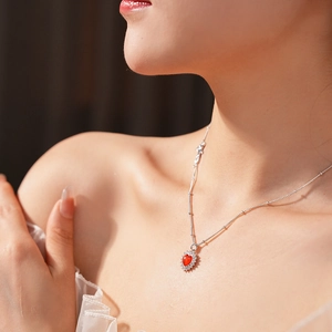 Detail of red heart pendant necklace with zircon border worn on a model's neck