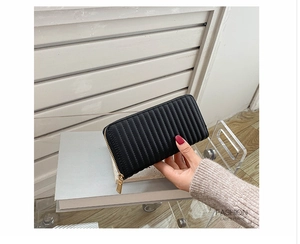 Close-up of black long PU leather purse with vertical quilted stitching and gold zipper
