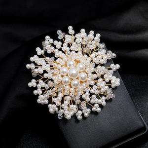 Macro shot of handmade gold wire brooch with white pearls and sparkling crystal beads