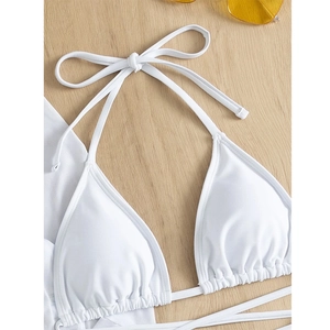 Detail view of white halter bikini top with strings on a light wood background