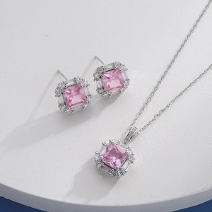Detail of silver jewelry set with square pink gemstones and sparkling halo accents