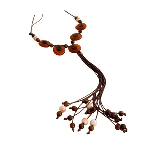 Handmade ethnic necklace with brown wooden beads and orange tassels on a white background