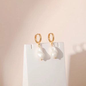 Detail of gold baroque pearl earrings with irregular natural texture and metallic hoop
