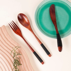 Detail of wooden cutlery set with black twine wrapped handles on flat lay background