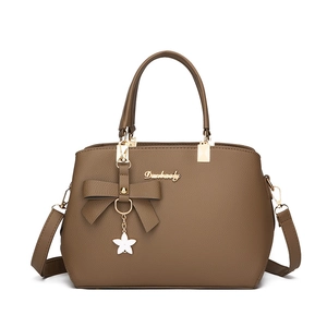 Brown leather tote bag with bow decoration and floral charm, dual handle design