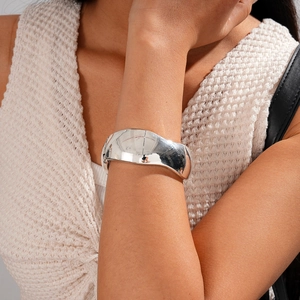 Close-up of modern silver wide wave cuff bracelet with a polished glossy finish