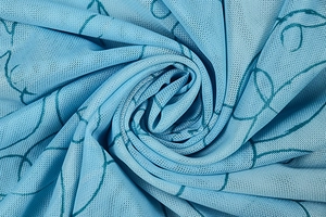 Macro shot of light blue mesh fabric with abstract dark cyan patterns and soft texture