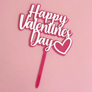 Macro detail of a pink Happy Valentine's Day acrylic cake topper with white heart pattern