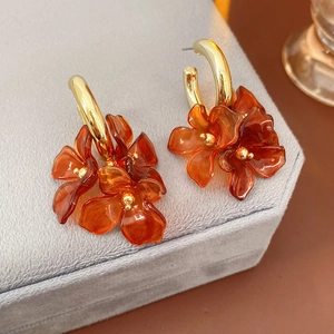 Detail shot of golden C-shaped flower petal earrings on a premium grey velvet jewelry box