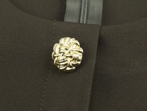Close-up of golden woven metal buckle and matching zipper on dark brown midi dress