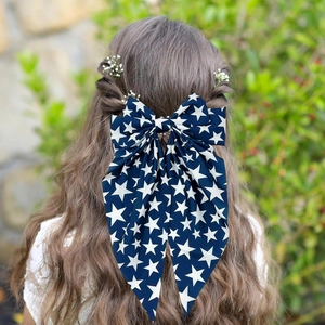 Close-up of a blue bow hair clip with white star pattern worn on model's hair