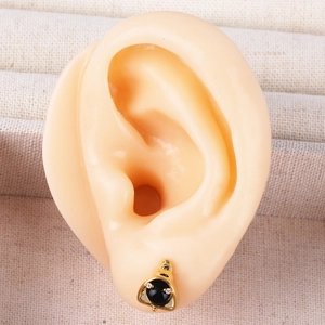 Detailed close-up of golden helmet earring with crystal accents on ear model