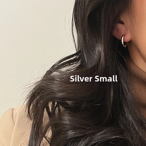 Close-up of small silver stainless steel hoop earring worn on model's ear