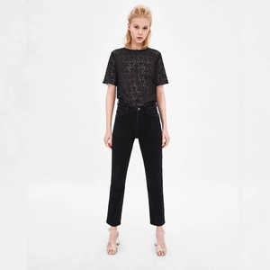 Elegante top in pizzo nero con bordi bianchi a contrasto e jeans neri a gamba dritta
