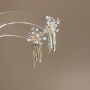 Detailed macro view of gold tassel earrings with pearls and sparkling zircon accents