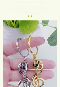 Detail of silver and gold music note keychains with microphone charms in hand