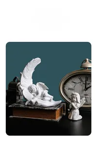 Close-up of white resin angel figurines with feather details and classical decor