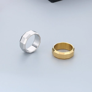 Macro detail of geometric multi-faceted cut rings in gold and silver stainless steel