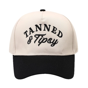 Two-tone baseball cap with beige crown, black brim, and TANNED & Tipsy embroidery