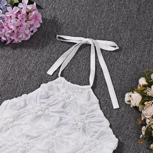 Detail view of white halter top featuring 3D floral pleated fabric and stylish tie straps