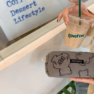 Corduroy pencil case with bear print and zipper closure held next to coffee cup