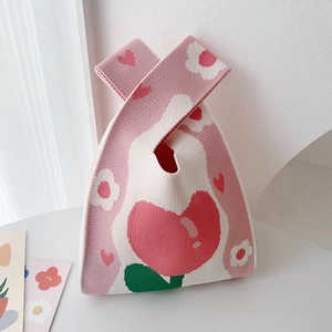 Close-up of pink knit tote bag with heart and flower patterns on a clean surface
