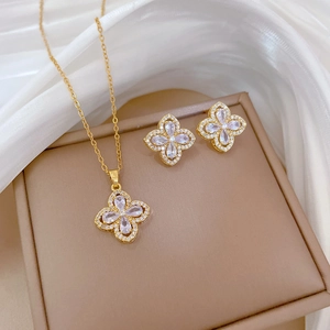 Luxurious gold clover jewelry set with sparkling zircons on elegant silk background