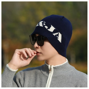 Outdoor shot of a navy blue knitted beanie featuring white A-IA pattern embroidery