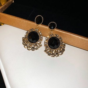 Close-up of vintage black rhinestone earrings with gold lace and faceted crystals