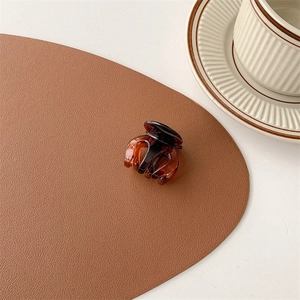 Close-up of a mini tortoiseshell hair claw clip on a premium leather desk mat