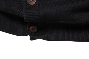 Detailed macro view of black knit fabric texture and brown button closure on cardigan