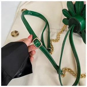 Détail du sac fleur vert montrant la texture cuir, chaîne dorée et couture fine