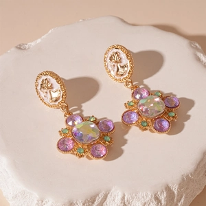 Close-up of vintage gold portrait relief earrings with colorful crystals and white accents