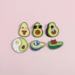 Flat lay of six colorful avocado enamel pins with various cute characters on pink background