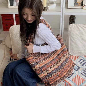 Detailed close-up of colorful striped knit tote bag with thick shoulder strap texture
